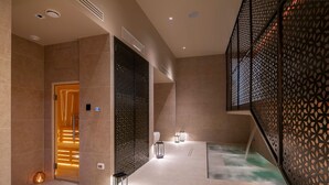 Un moderno espacio de spa con un jacuzzi, una puerta de madera y faroles decorativos.