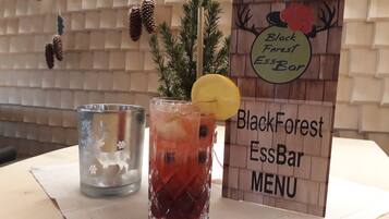 A menu board for BlackForest EssBar, a glass of iced tea with a lemon slice, and a glass of water on a table.