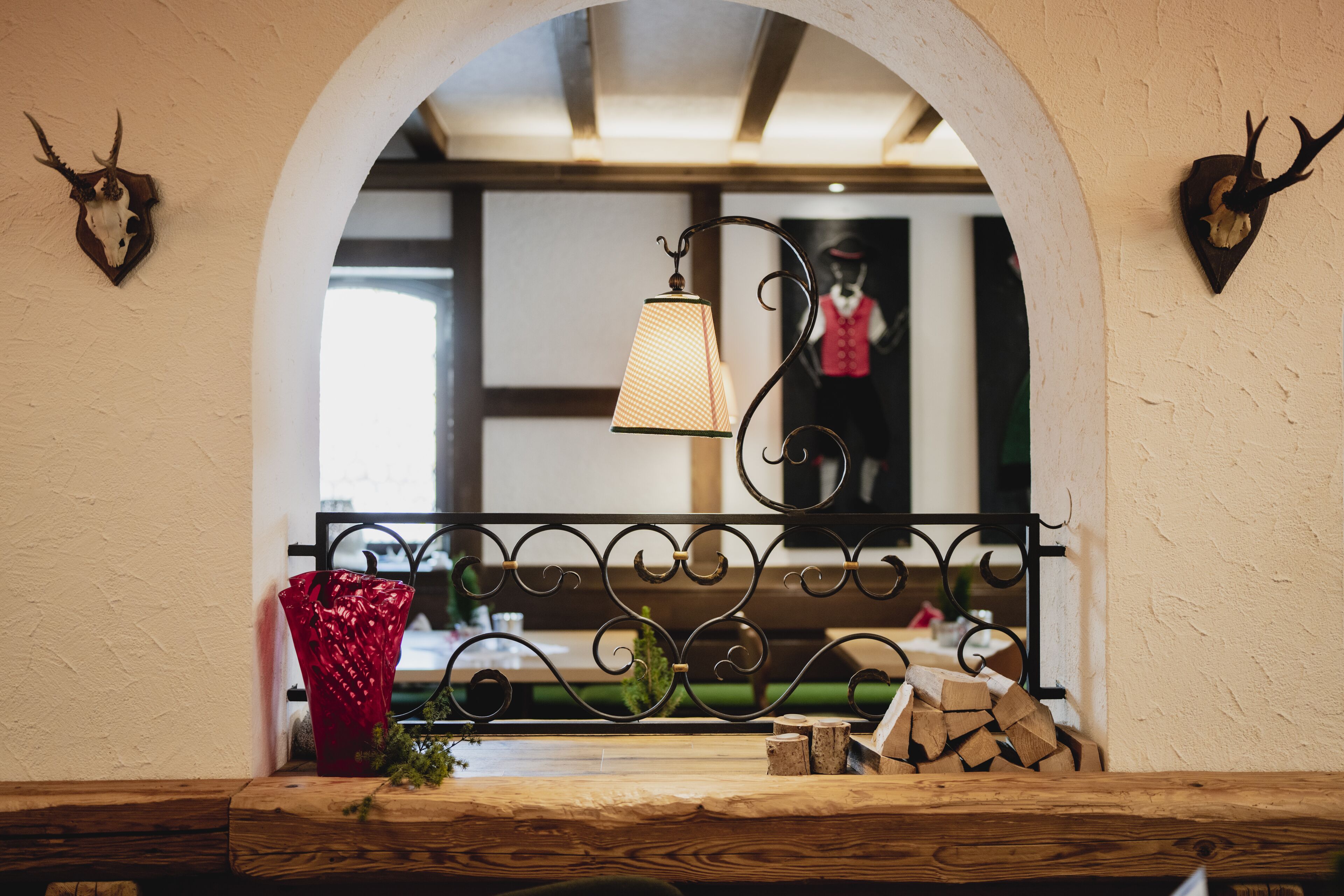 Ein rustikales Interieur mit einem Holztisch, einer roten Vase und Geweihdekorationen.