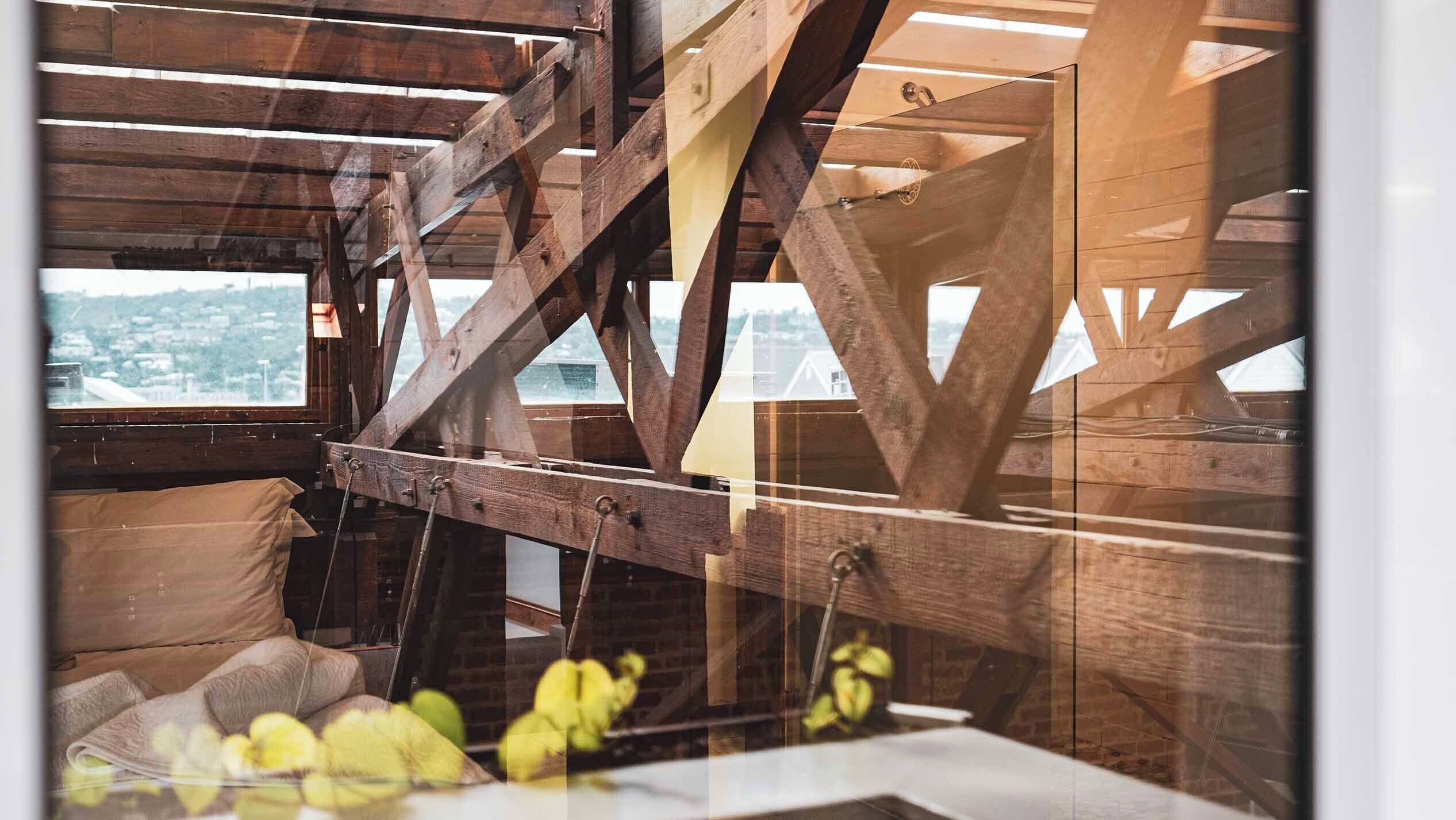 A room with exposed wooden beams and a view of a cityscape through a window.