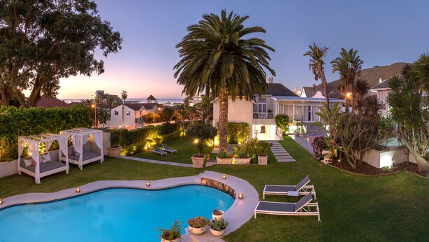 A pool area with a curved pool, lounge chairs, and a pergola with a canopy. - The Clarendon - Fresnaye (Cape Town)