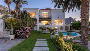 A modern two-story house with a swimming pool, a well-maintained garden, and a stone pathway leading to the entrance. - The Clarendon - Fresnaye (Cape Town)