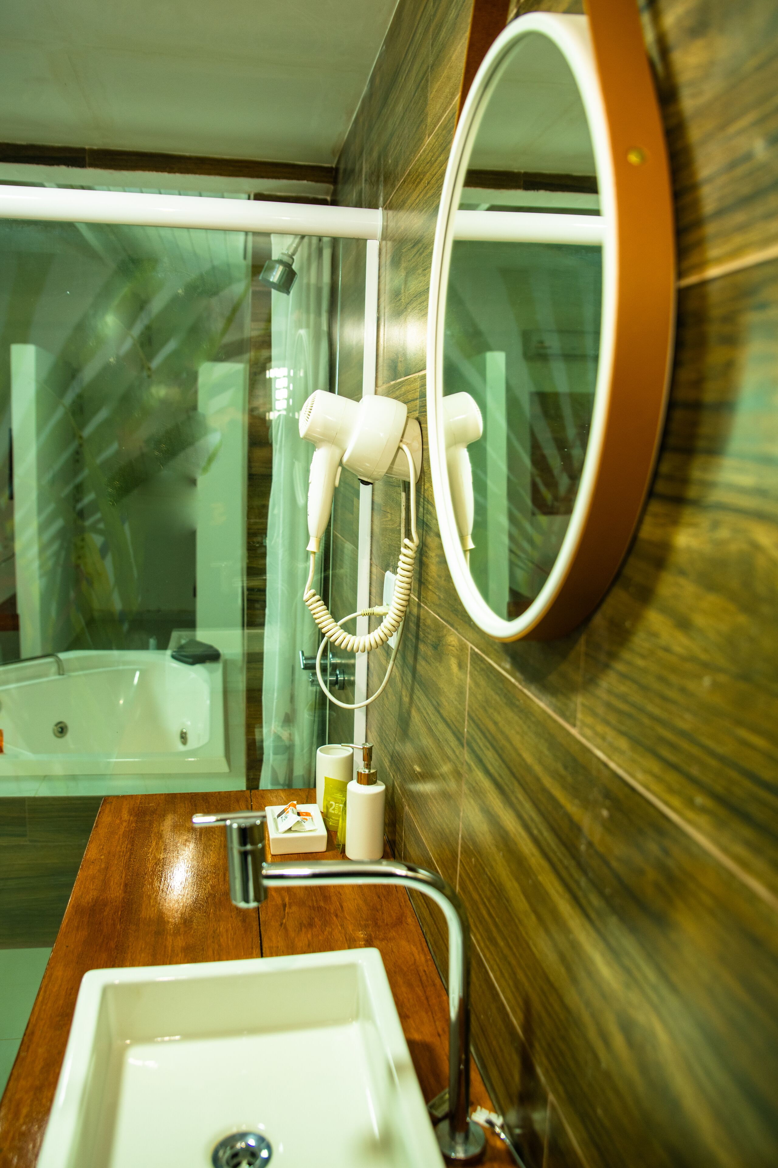 Un baño con tocador de madera, lavamanos blanco, espejo y secador de pelo montado en la pared.