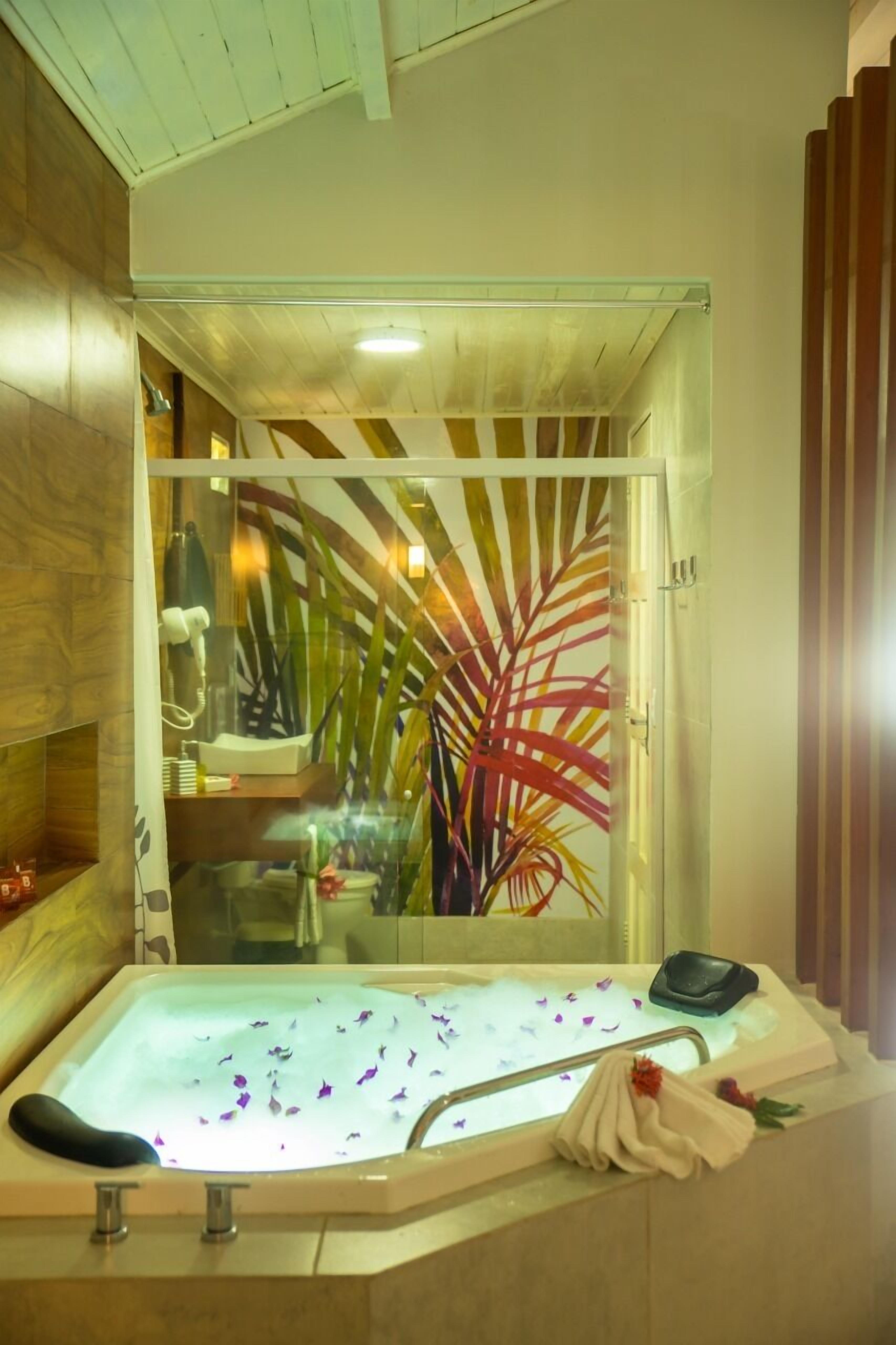 Een moderne badkamer met een douchecabine, een bad gevuld met rozenblaadjes en een houten wastafelmeubel.