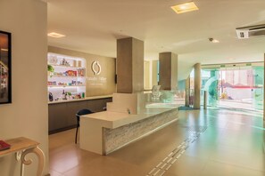 Ein Hotel-Empfangsbereich mit Theke, Sitzgelegenheiten und einem Glastür-Eingang.