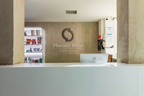 Una recepción con un cartel que dice 'Planalto Bittar Hotel e Eventos' y un refrigerador lleno de bocadillos.