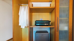 Una habitación compacta con un armario de madera, un refrigerador negro pequeño y una toalla blanca colgada en la puerta.