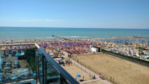 Egy strand, ahol rengeteg napernyő és napozóágy található, ahonnan tiszta kilátás nyílik az óceánra, és egy sétaút húzódik a part mentén.