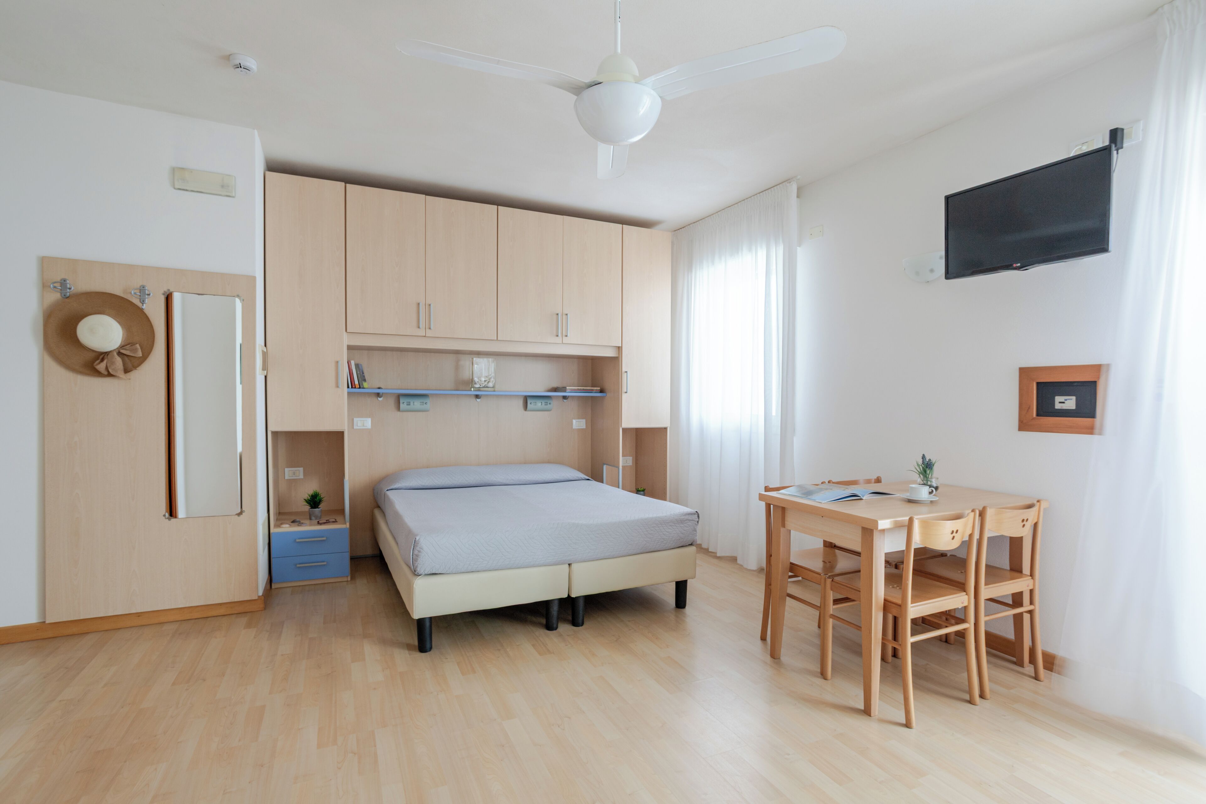 Une chambre à coucher avec un lit, un bureau et un ventilateur de plafond.
