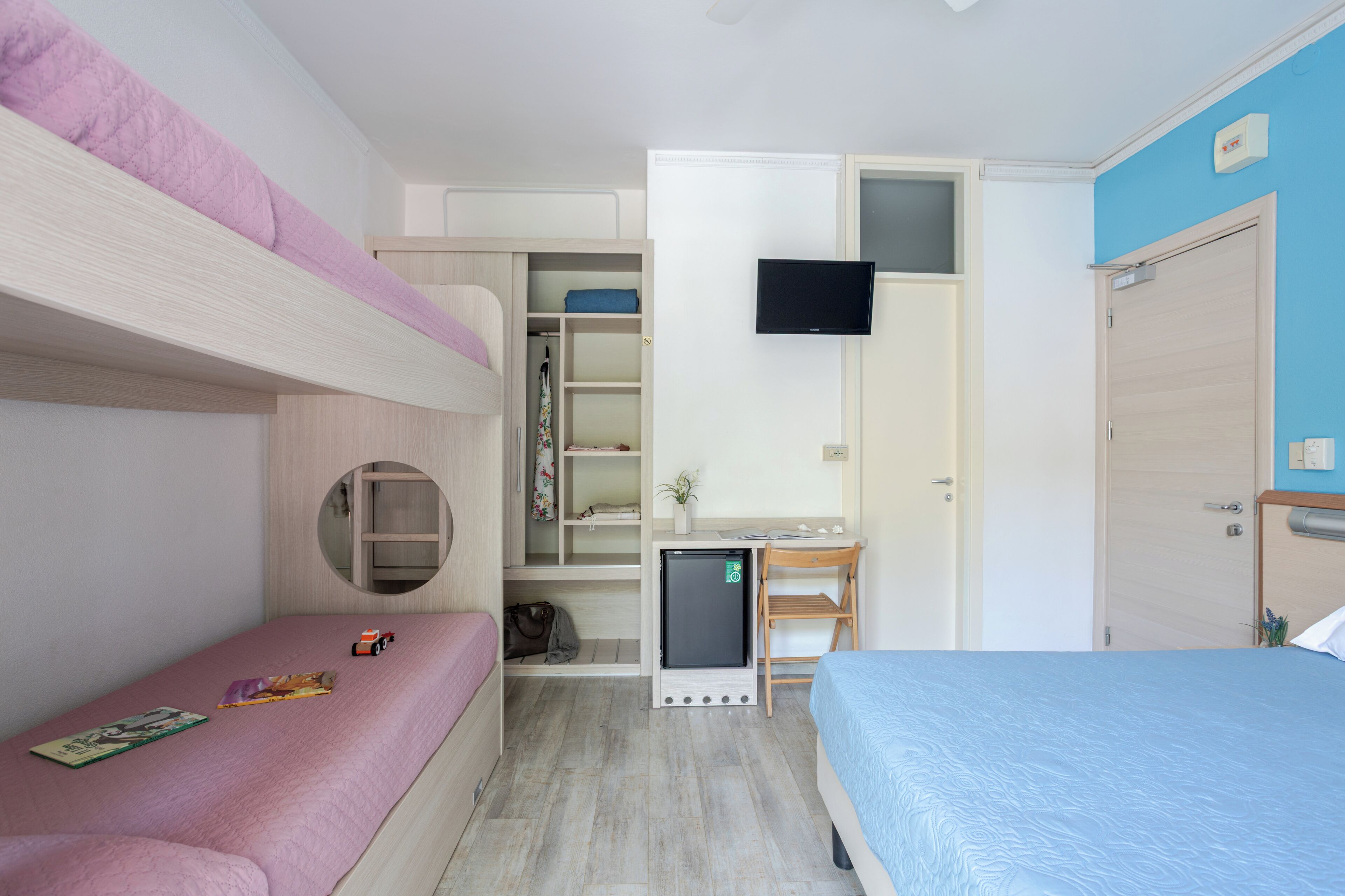 Un dormitorio con literas, un escritorio, un televisor y un armario.