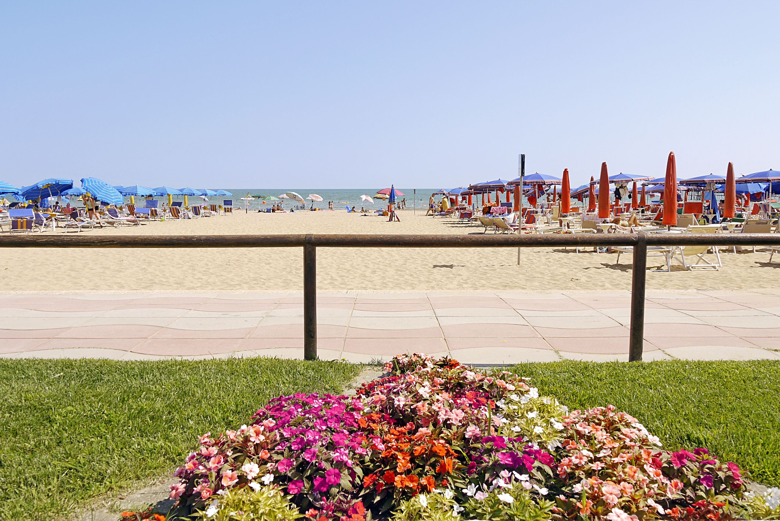 Aan een privéstrand, wit zand, ligstoelen, parasols