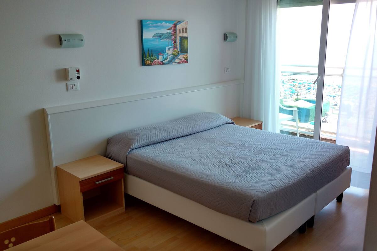 A neatly arranged bedroom with a bed, bedside tables, and a painting on the wall.