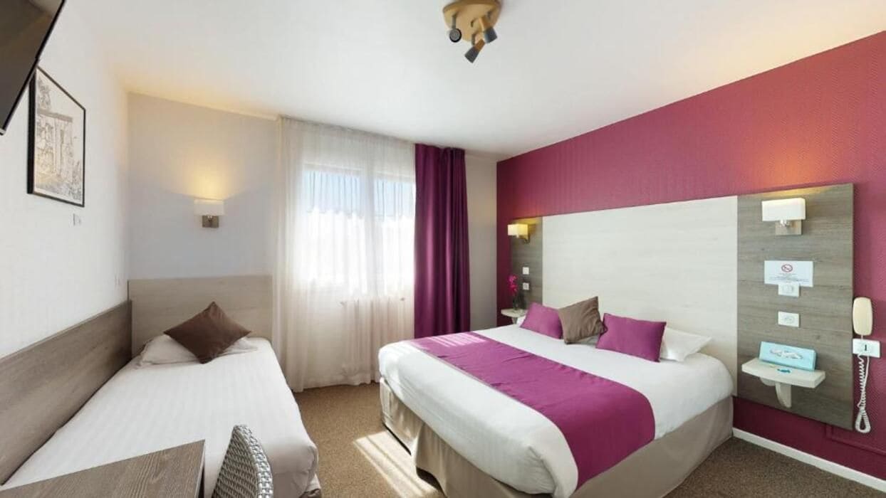 Ein Hotelzimmer mit zwei Betten, einem Nachttisch mit Lampe, einem Spiegel und einem Telefon an der Wand.