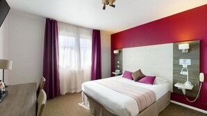 A hotel room with a bed, a desk, a telephone, and a window with curtains. - HÔTEL PRADO - TOULOUSE HIPPODROME (Toulouse)