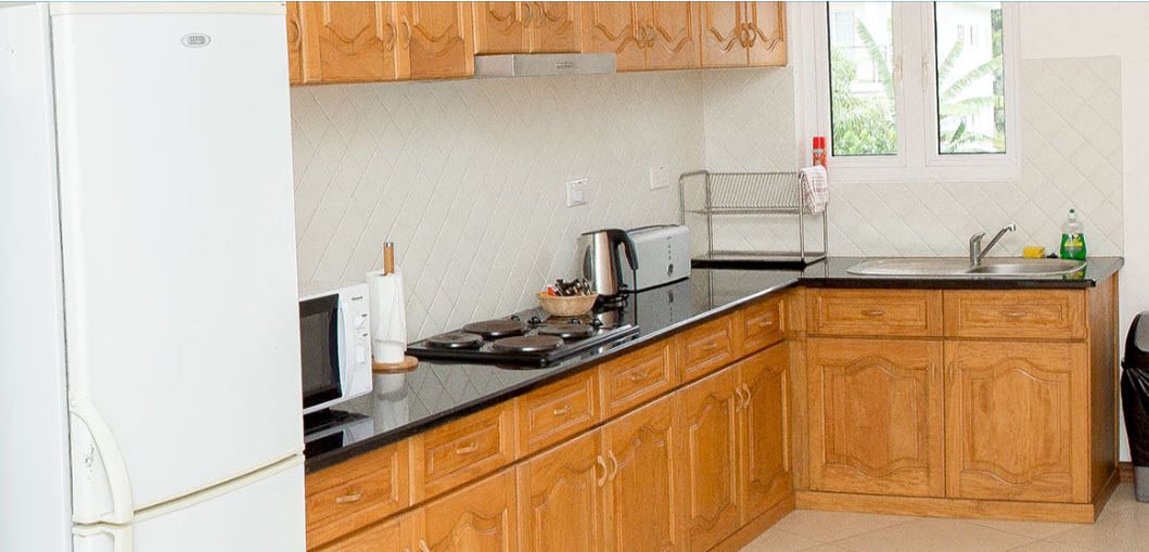 A kitchen with wooden cabinets, a black countertop, a stove, and a sink.