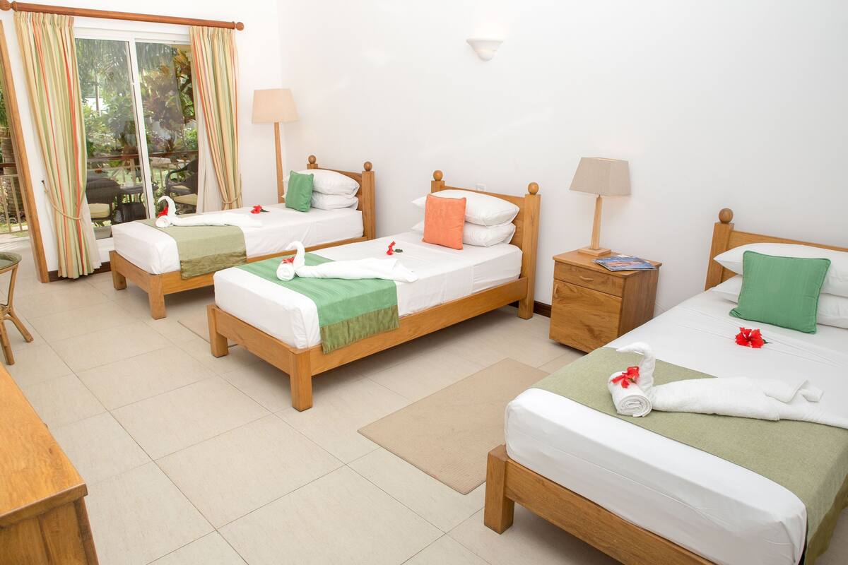 A hotel room with two single beds, a wooden nightstand, a desk, and a chair.