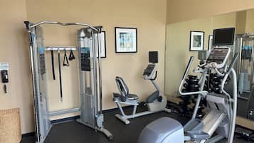 A gym with various exercise equipment, including a treadmill, elliptical, and weight machines.