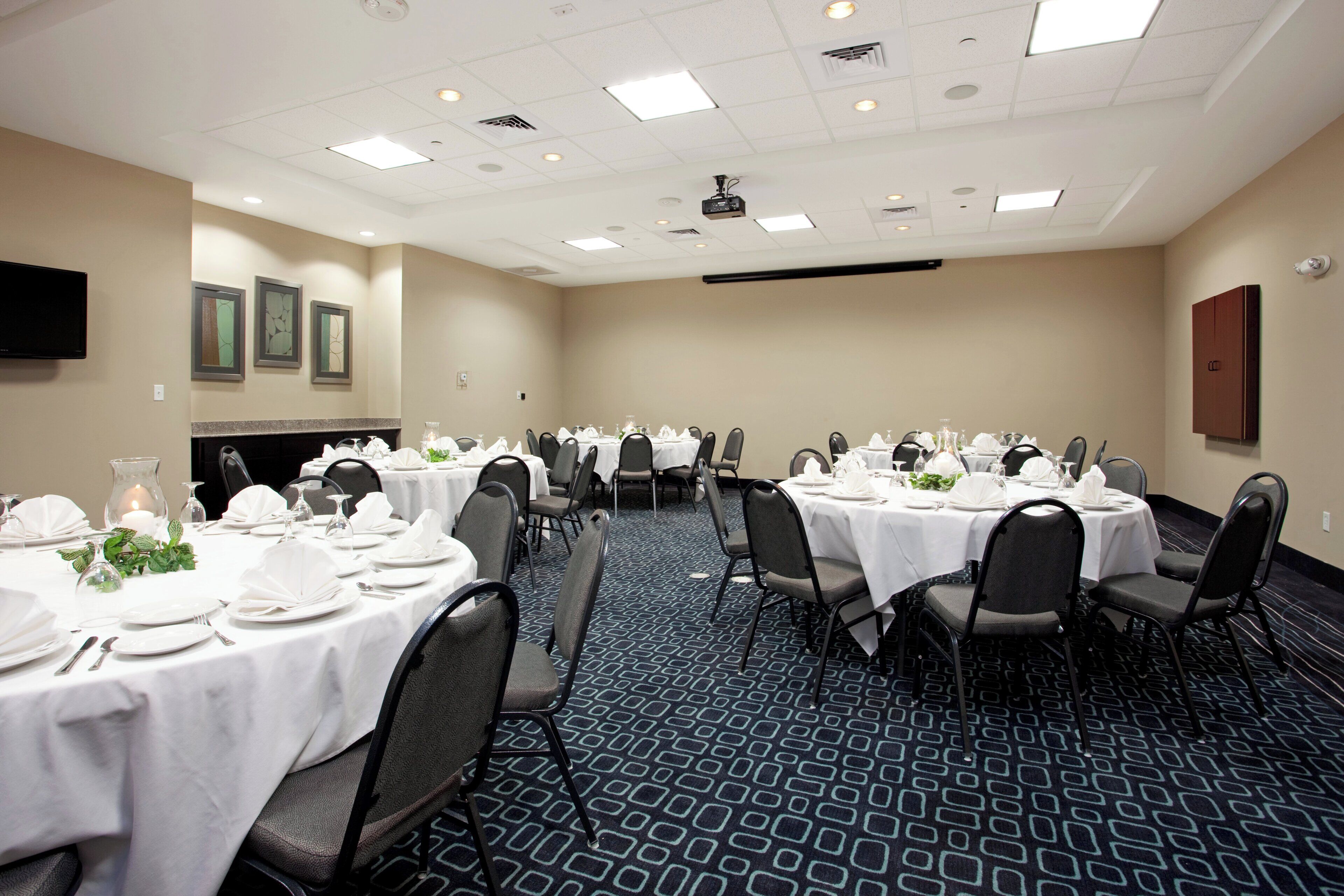 A conference room with round tables, chairs, and a projector screen.