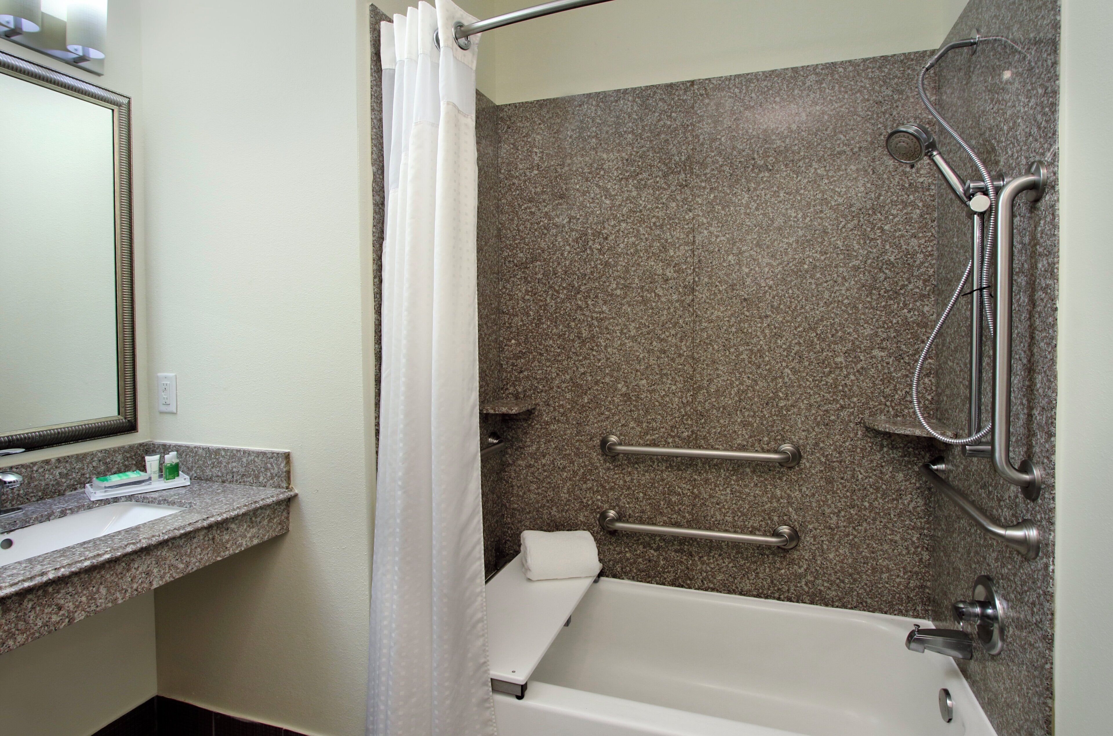 A bathroom with a bathtub, shower, and a vanity with a mirror.