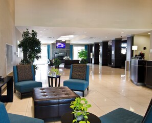 A spacious lobby with seating, a television, and a reception desk. - Holiday Inn Hammond by IHG (Hammond)