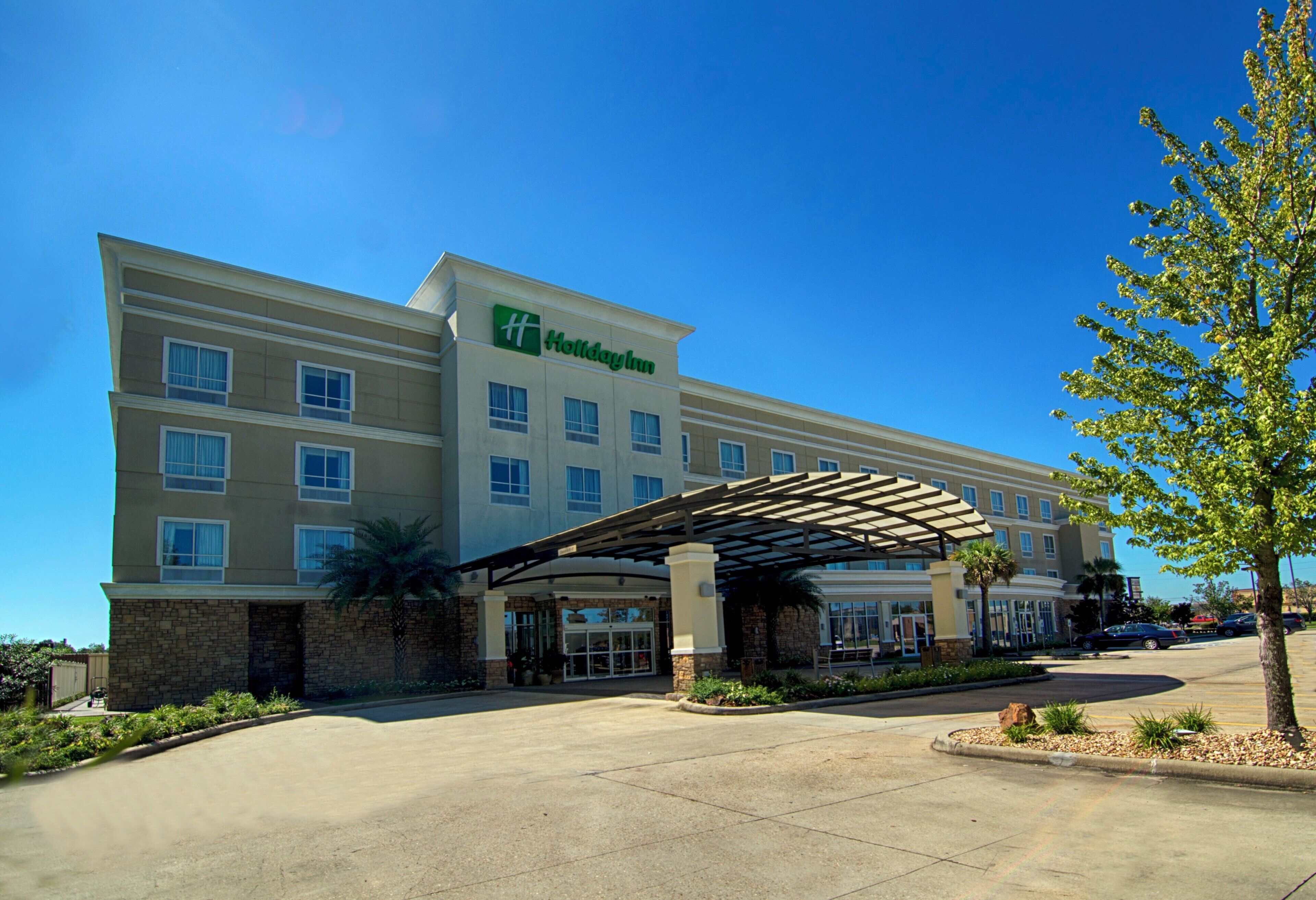 A Holiday Inn hotel with a covered entrance and a parking lot.