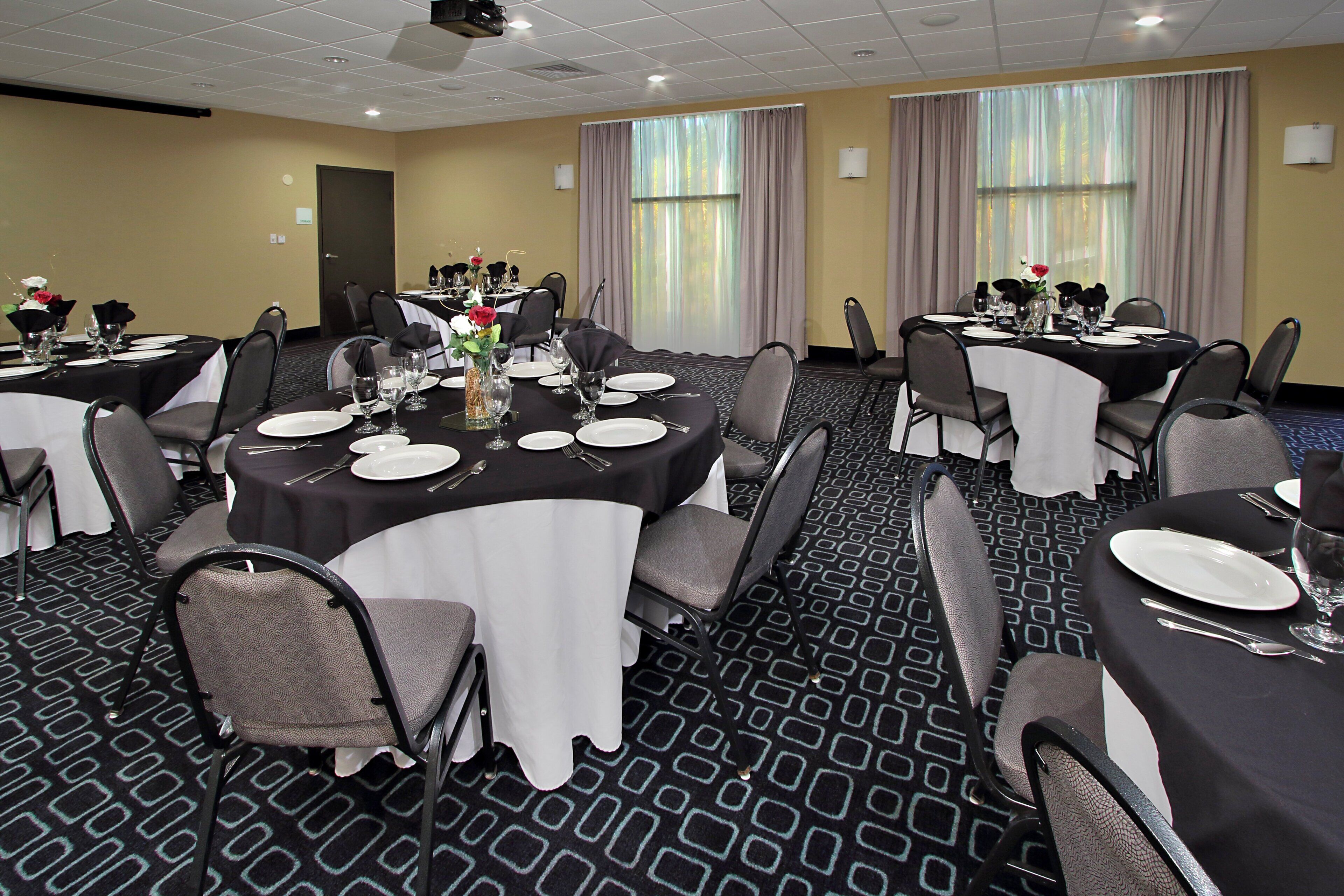 A conference room with multiple tables set for dining, equipped with chairs and table settings.