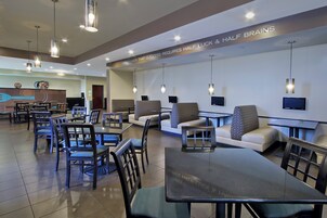 A modern restaurant with seating arrangements, tables, and hanging lights.