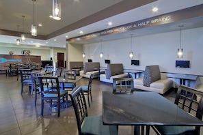 A modern restaurant with seating arrangements, tables, and hanging lights.