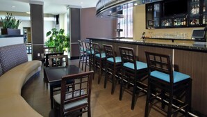 A modern hotel lobby with a bar area, seating arrangements, and a large plant. - Holiday Inn Hammond by IHG (Hammond)