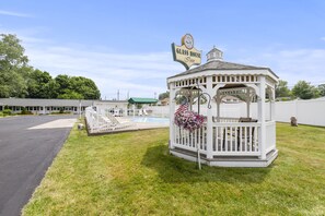 A gazebo-style structure with a sign reading "Glass House Inn" and an American flag. - Glass House Inn Erie Near I-90 & I-79 (Erie)