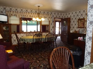 A dining room with a table and chairs, a chandelier, and a patterned carpet.