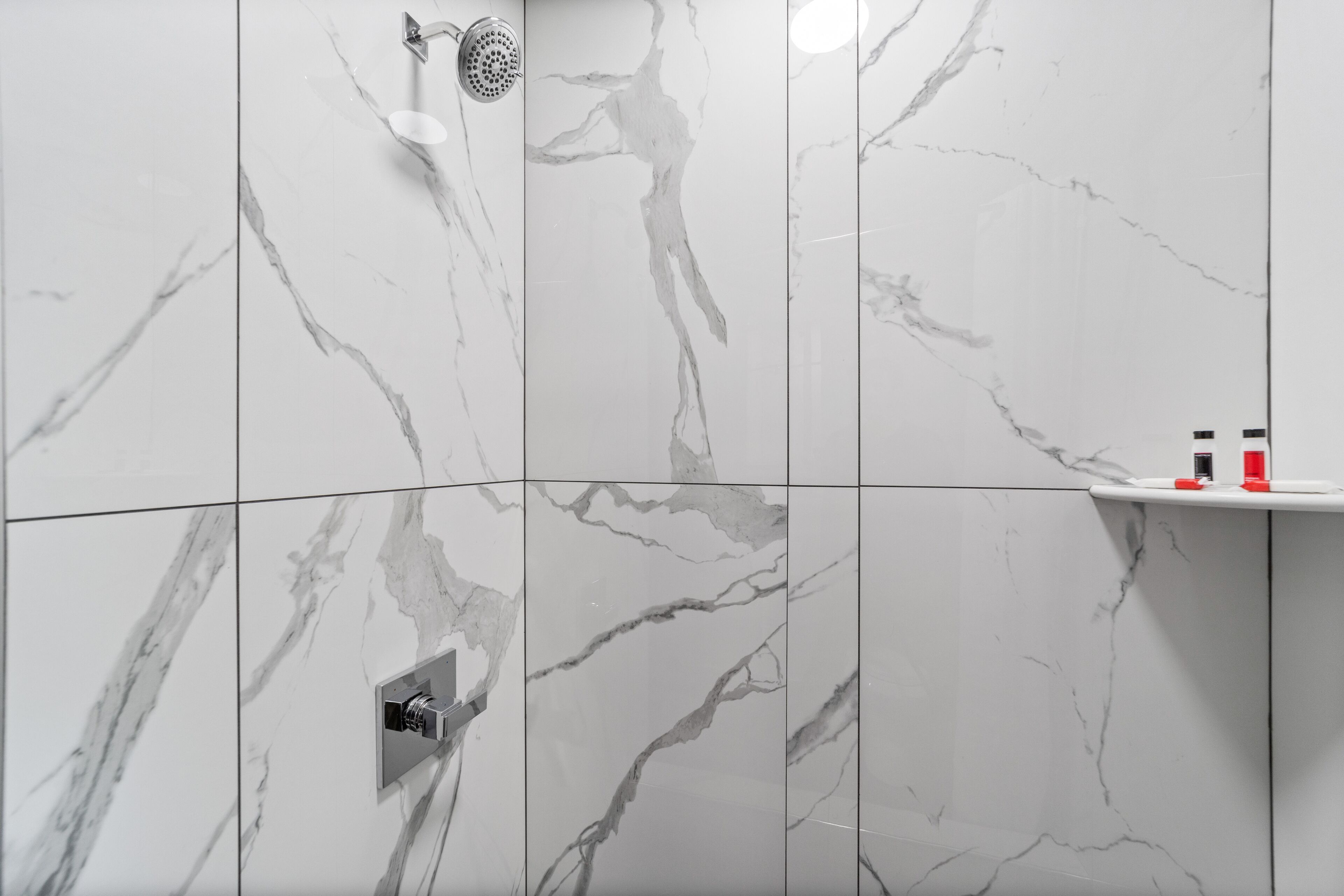 Une salle de bain avec des murs en marbre et une douche.