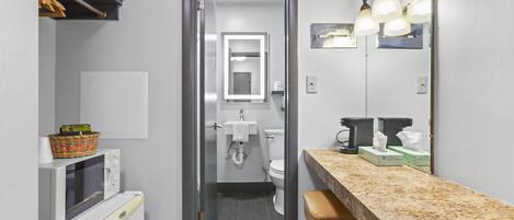 A compact bathroom with a toilet, sink, and a microwave.