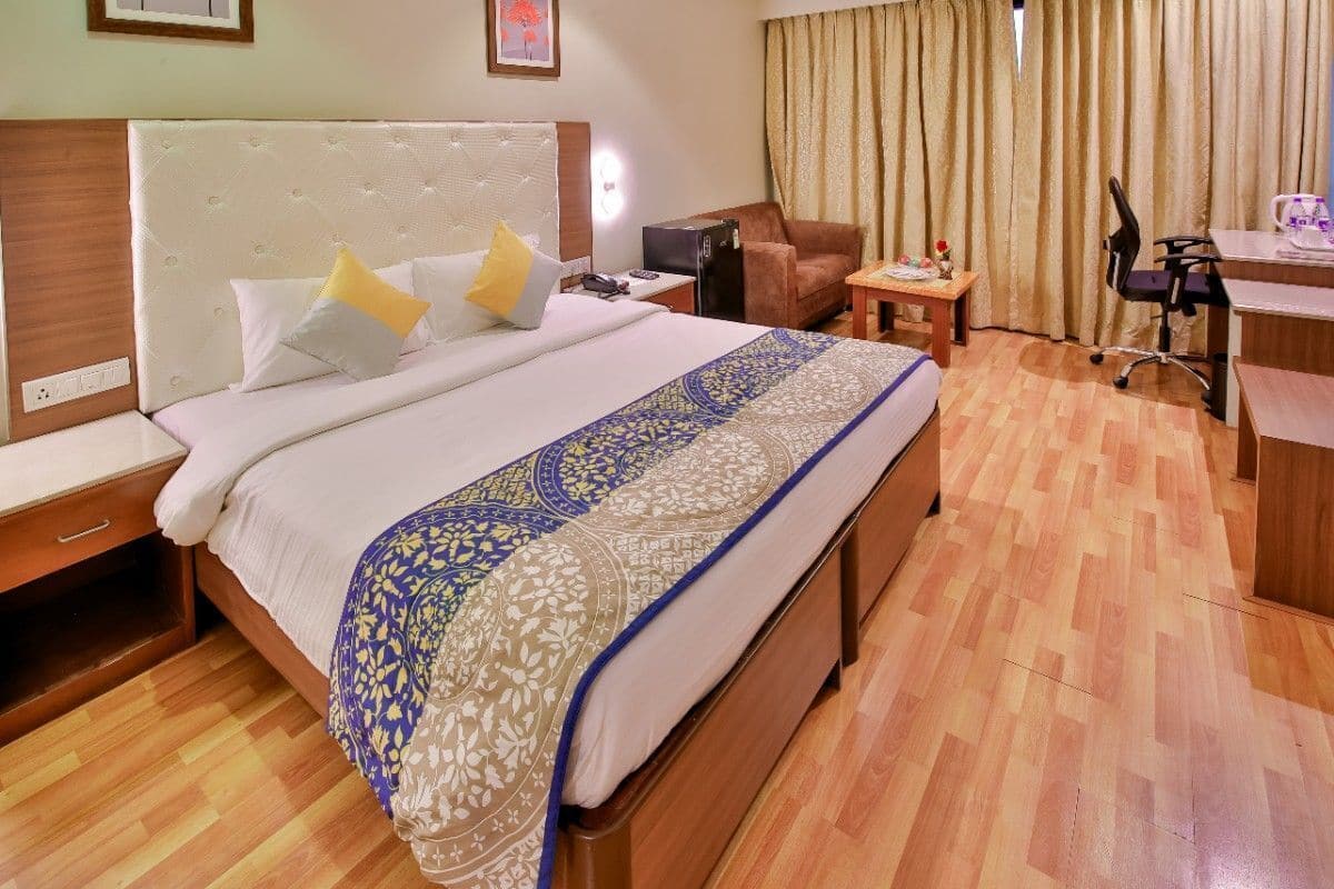 A hotel room with a large bed, a desk, a chair, and a sofa.