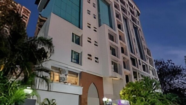 A multi-story hotel with a modern design, featuring a prominent entrance with a large archway and a well-lit facade. - The Caliph Hotel (Mumbai)