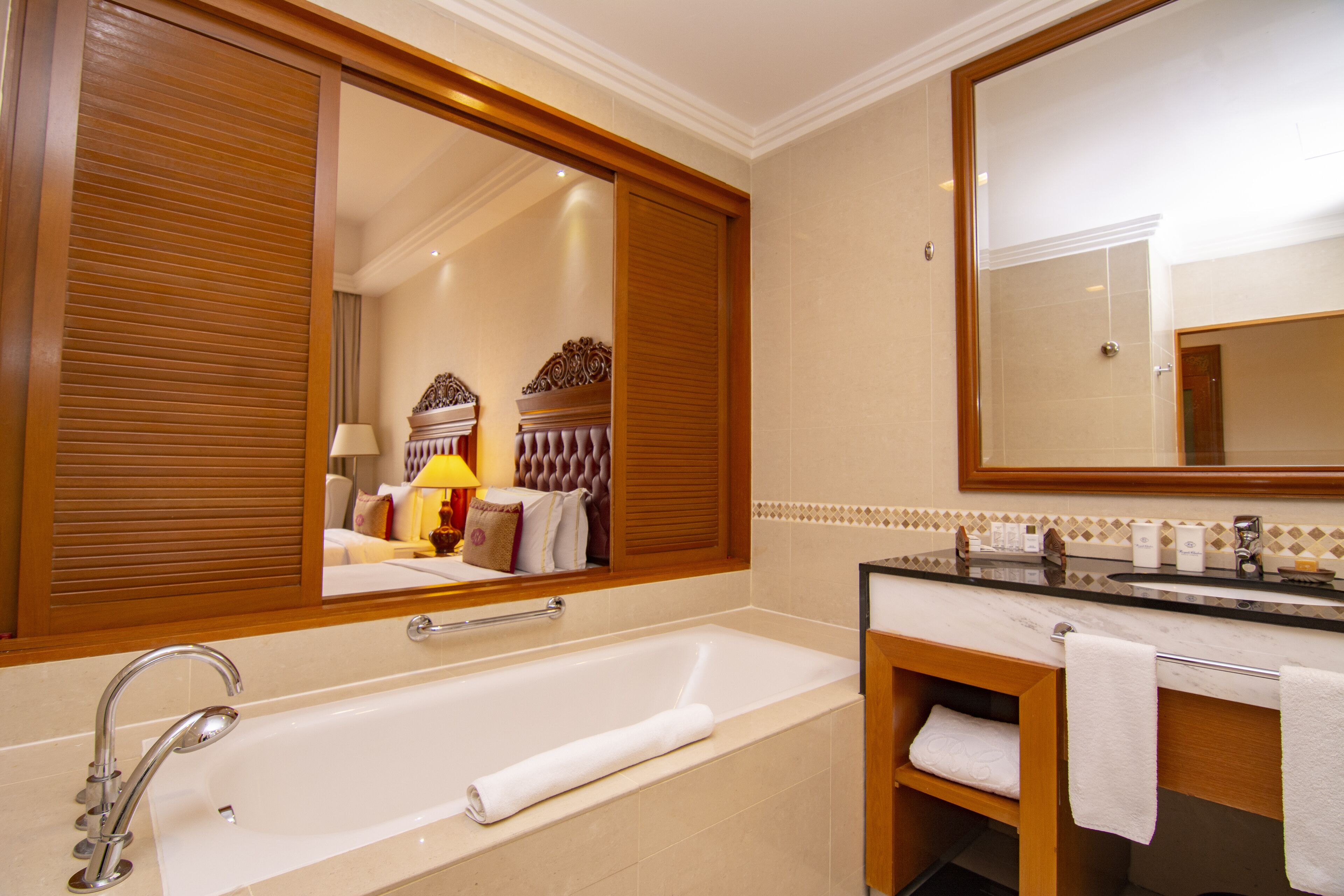A modern bathroom with a large mirror, a bathtub, a vanity with a sink, and a towel rack.