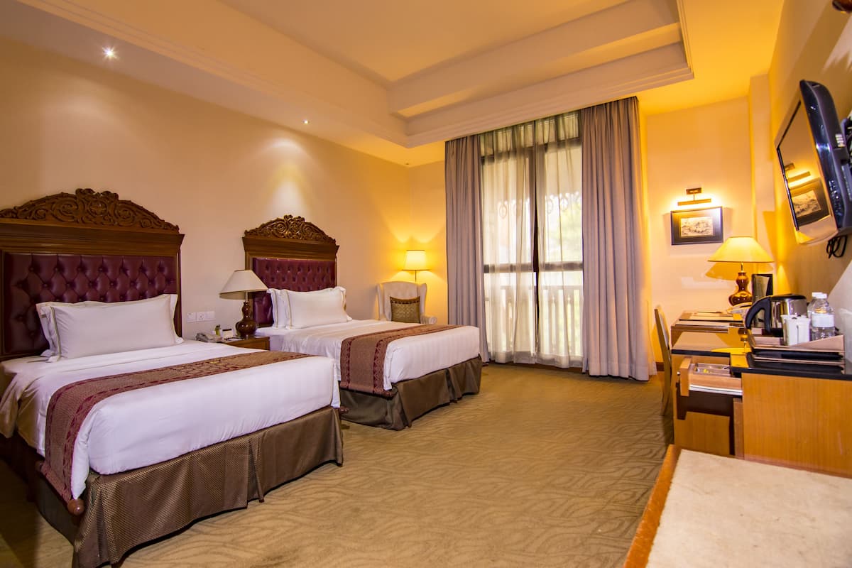 A hotel room with two beds, a desk, and a chair.
