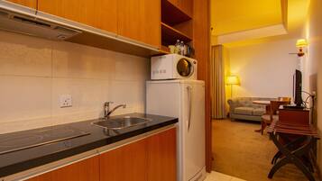 A compact kitchen with a built-in microwave, a sink, and a refrigerator. There is a dining area with a table and chairs.