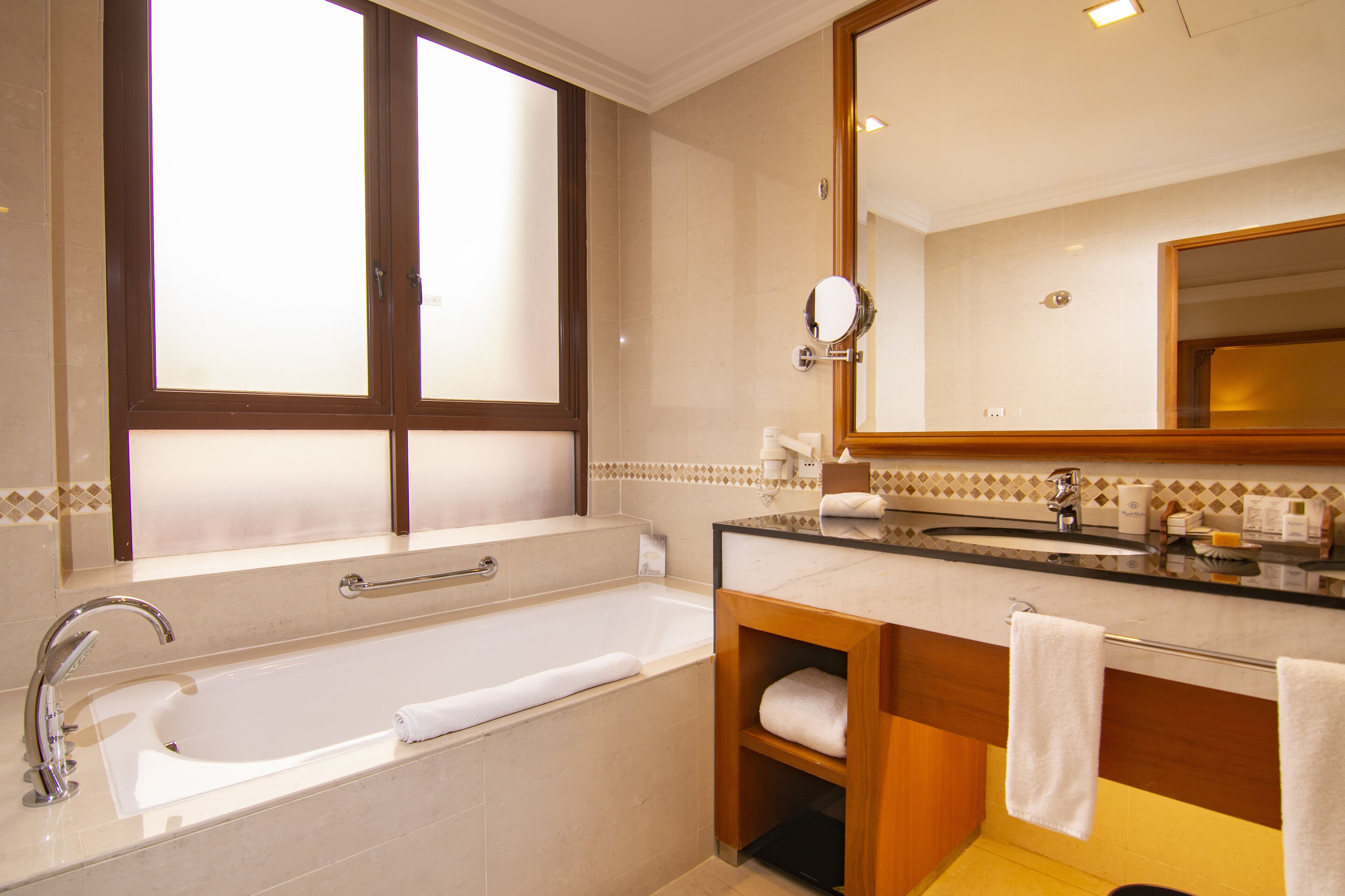 Un bagno moderno con una vasca da bagno spaziosa, un mobile vanitario con uno specchio e una finestra con vetro acidato.