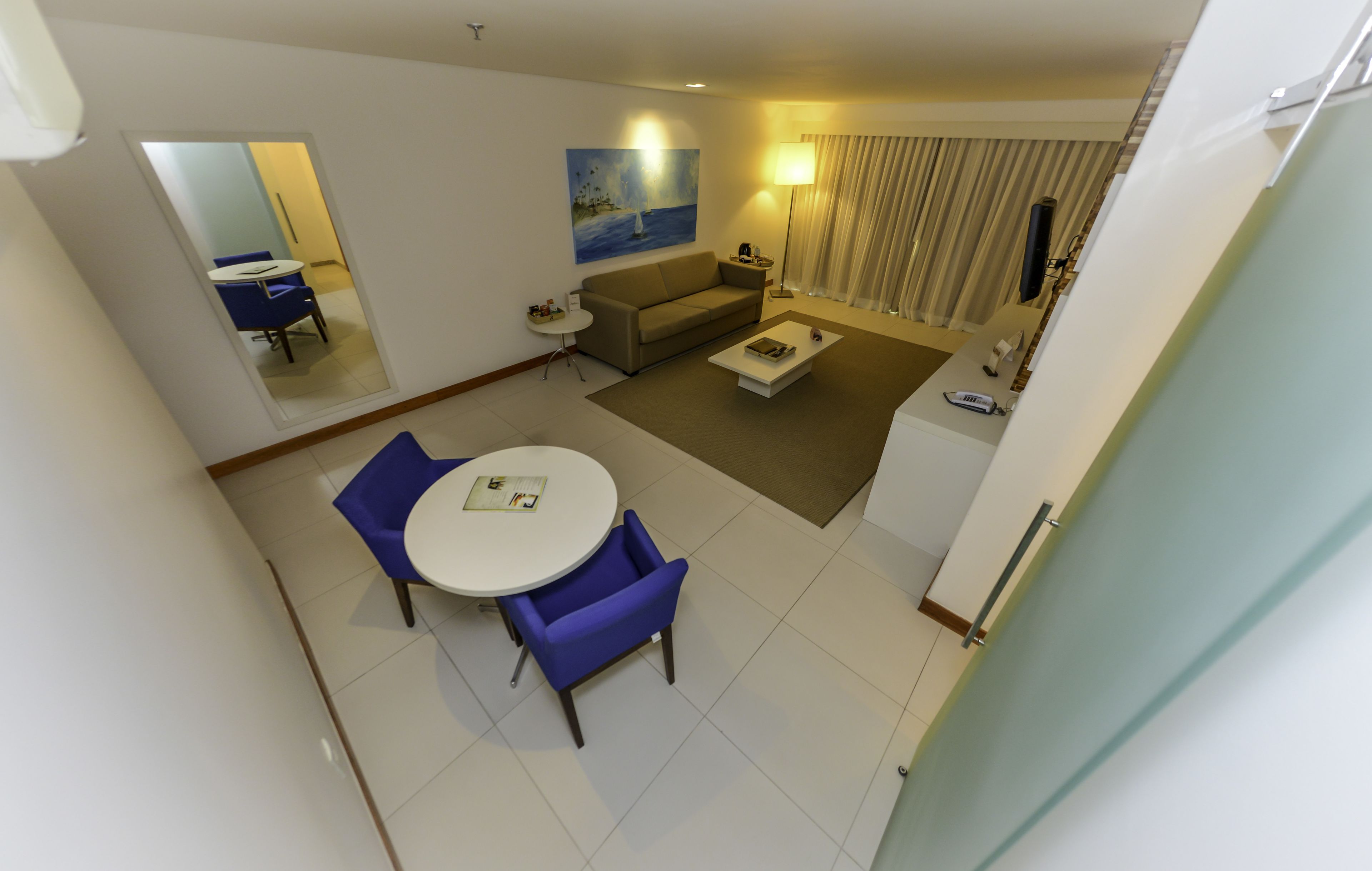 A modern living room with a sofa, coffee table, and a dining area with chairs.