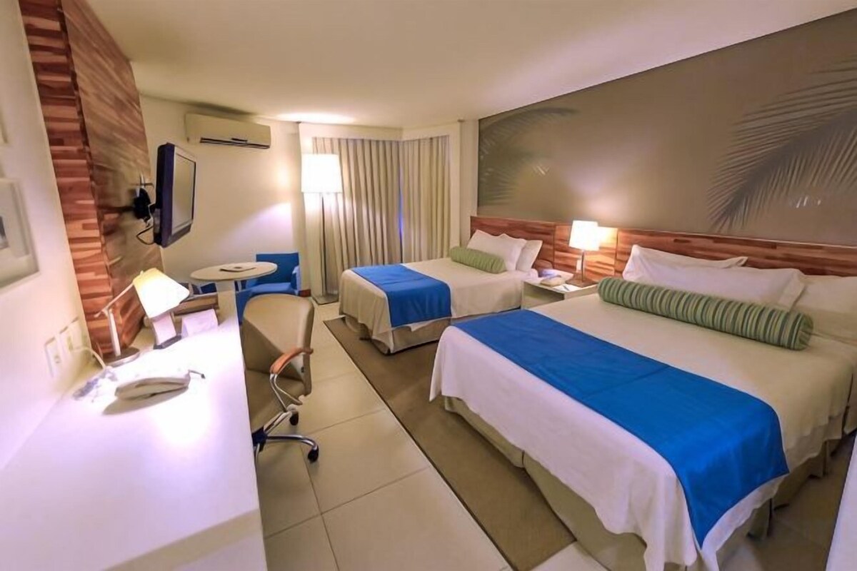 Una habitació d'hotel amb dos llits, un escriptori amb telèfon, una cadira i una taula petita.