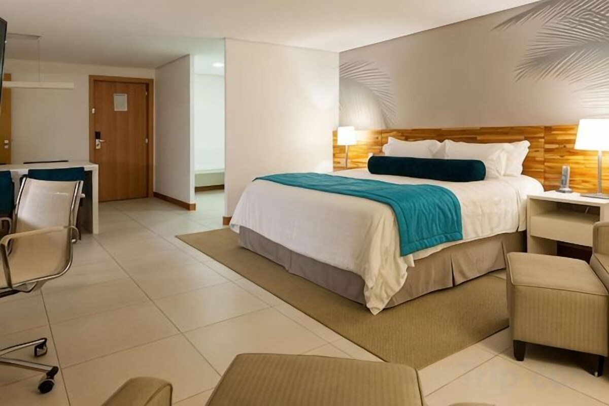 Una habitació d'hotel amb un llit, taules de nit, escriptori i una cadira.