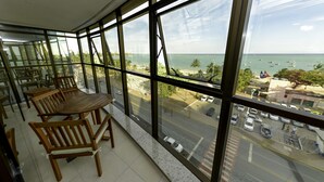 Un balcon doté de mobilier en bois et offrant une vue sur la mer et le paysage urbain.