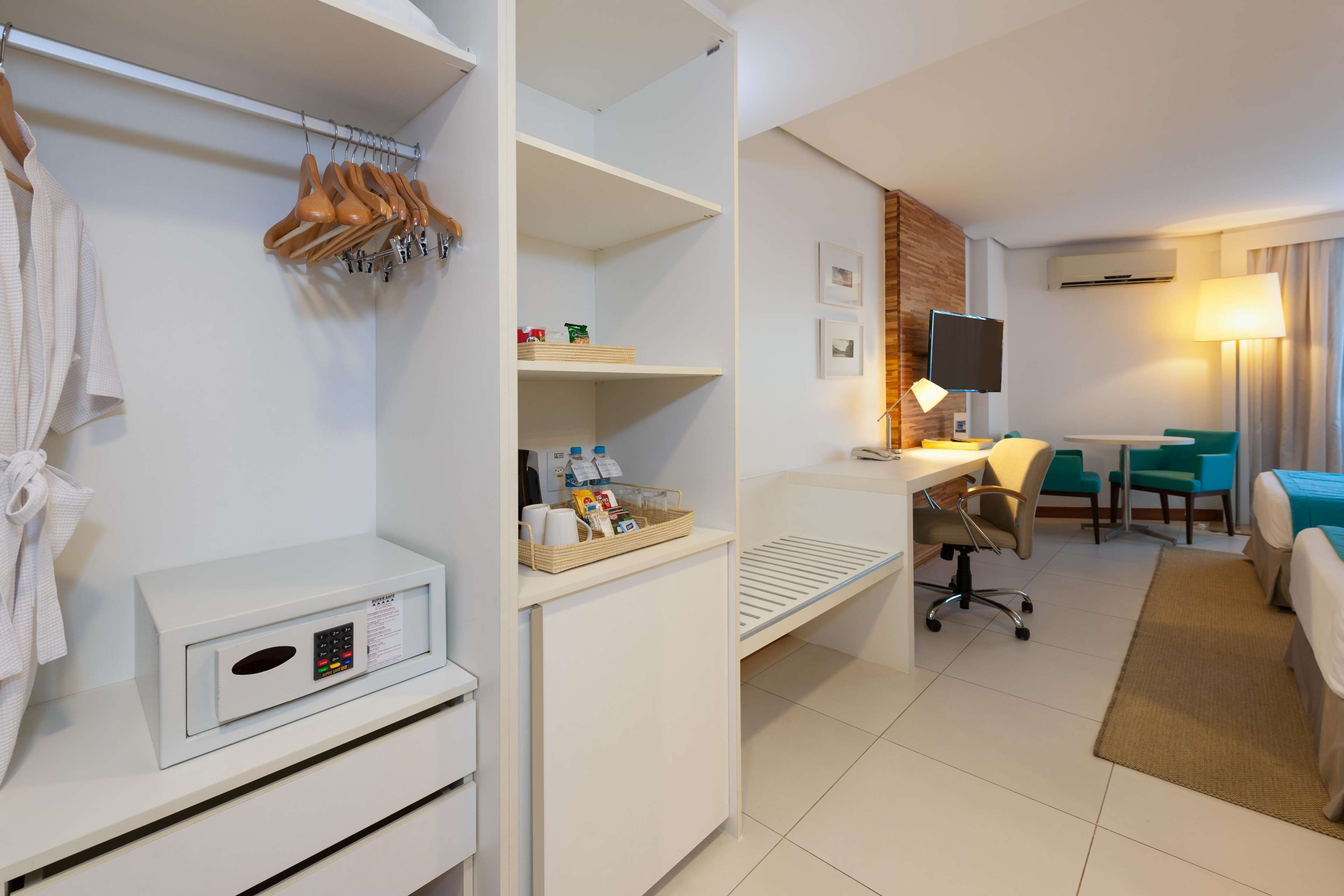 Habitación de hotel con armario, escritorio con silla, televisión y cama.
