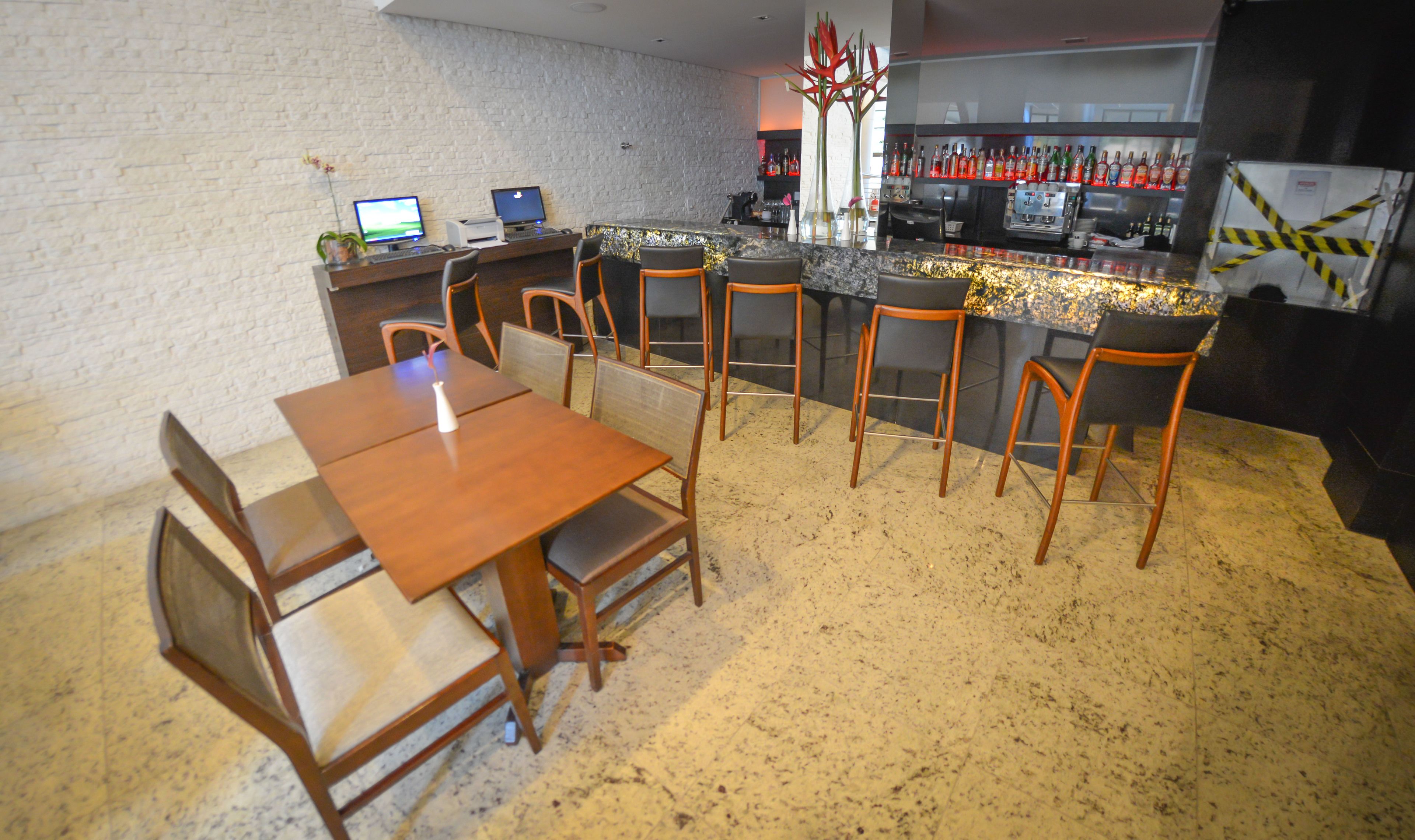 Un restaurante con zona de bar, mesas y sillas de madera, y una barra con una variedad de botellas.