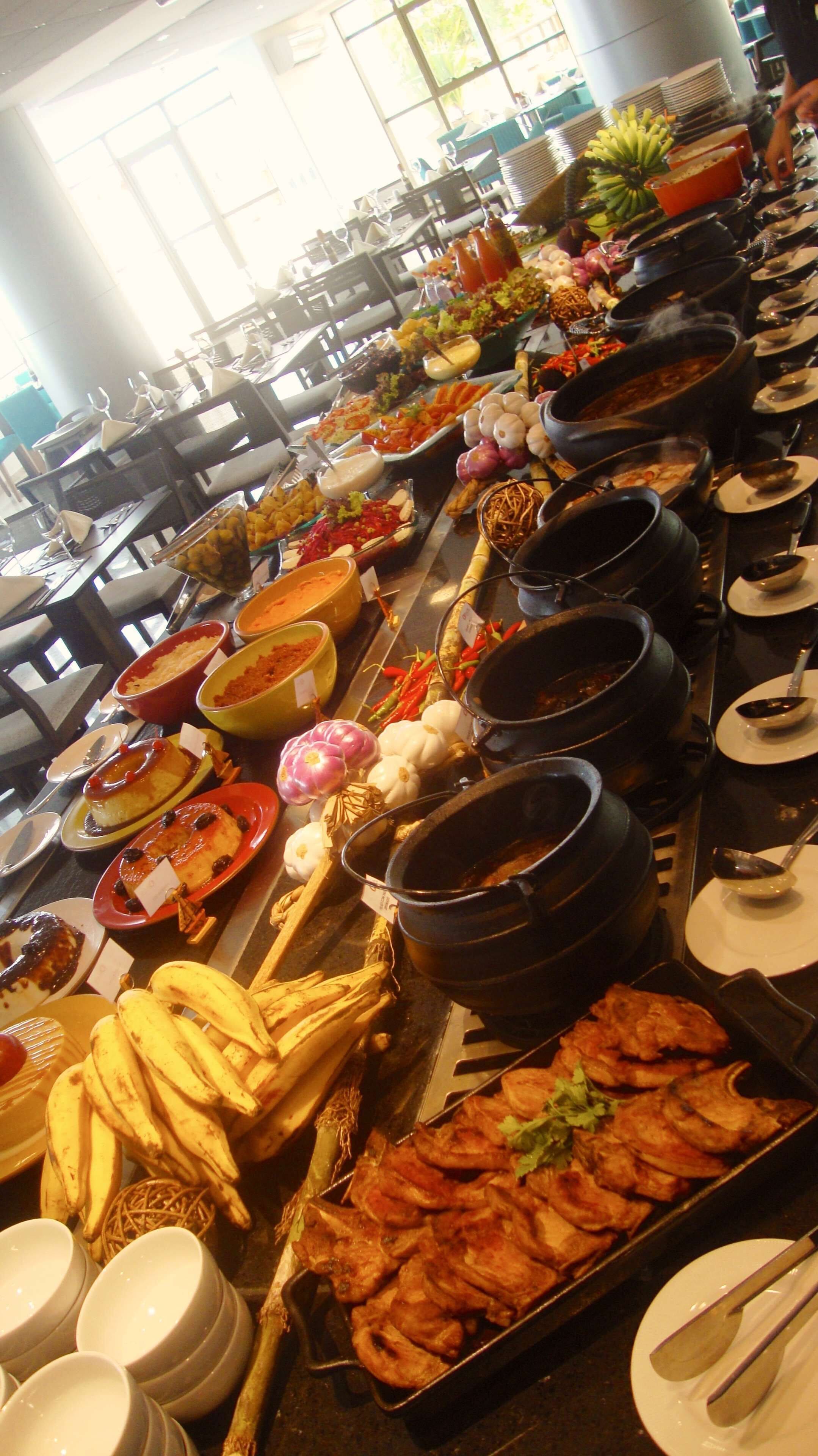 Buffet com diversos pratos, incluindo carnes, legumes e sobremesas.