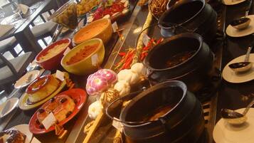 Buffet com diversos pratos, incluindo carnes, legumes e sobremesas.