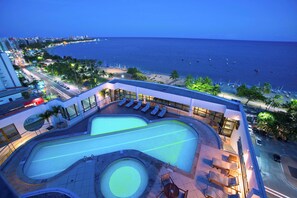 A swimming pool with a heart-shaped design, surrounded by lounge chairs and a small table, overlooking a beach and ocean. - Best Western Premier Maceió (Maceió)