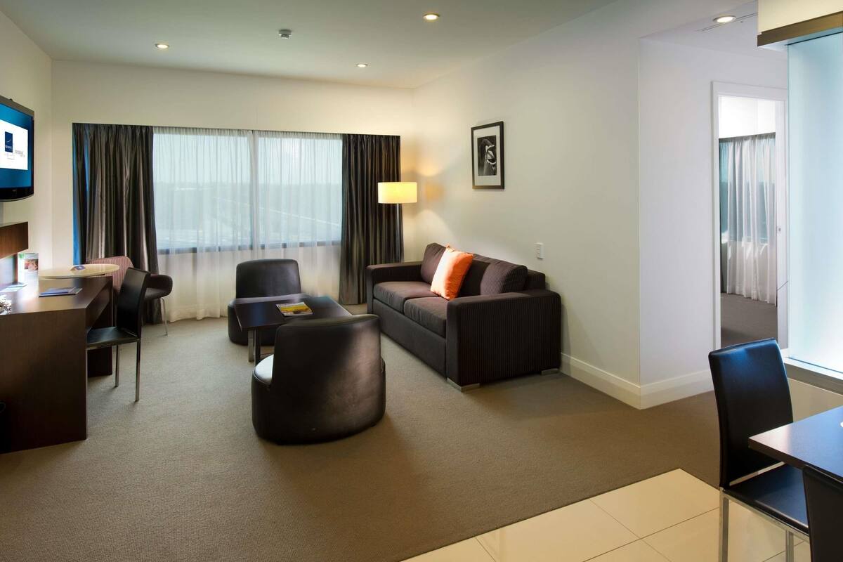 Une chambre d’hôtel équipée d’un canapé, d’un fauteuil, d’un bureau et d’une télévision.