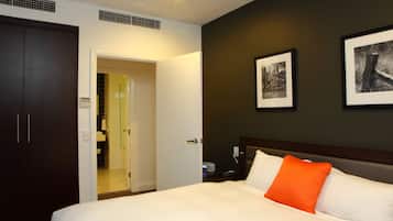 A hotel room with a bed, a nightstand, a wardrobe, and a bathroom visible through an open door.